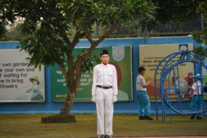 Seorang petugas upacara berdiri tegap di sisi lapangan, siap menjalankan tugasnya
